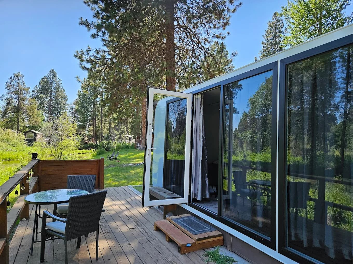 Modern capsule with open door onto a private deck with table and chairs