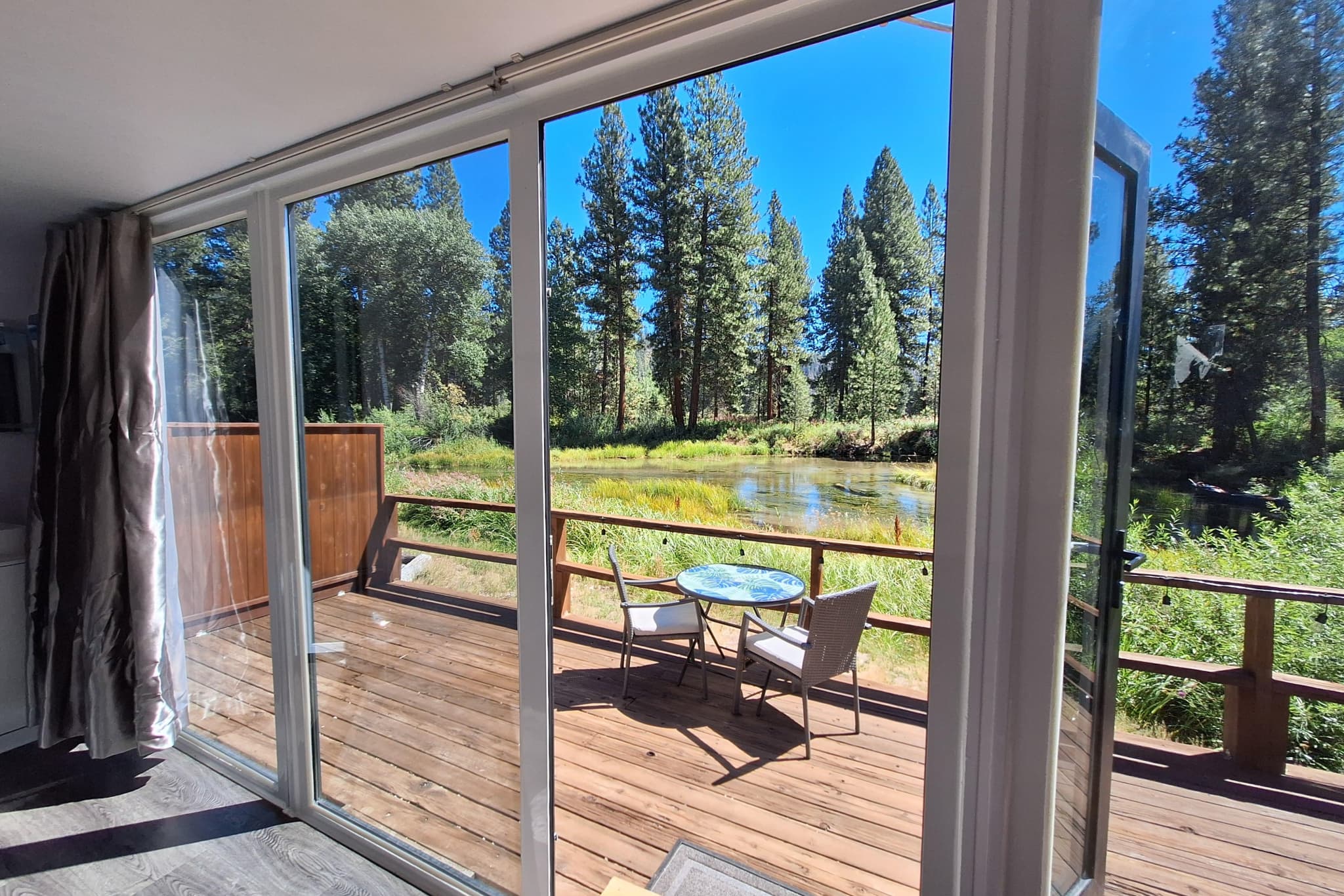 Looking out from inside the capsule onto the deck, the lagoon, and pines