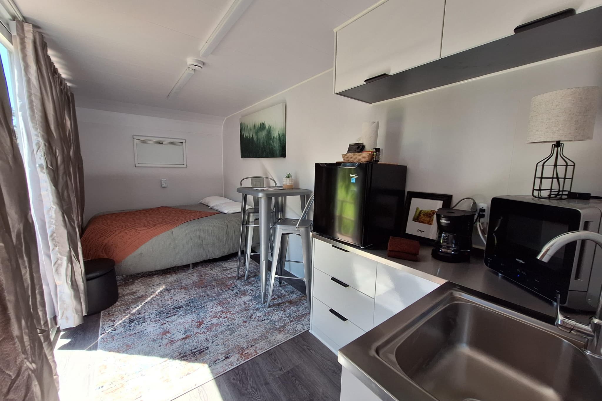Inside the capsule — full bed, dining nook, and kitchenette with fridge, microwave, and coffee maker
