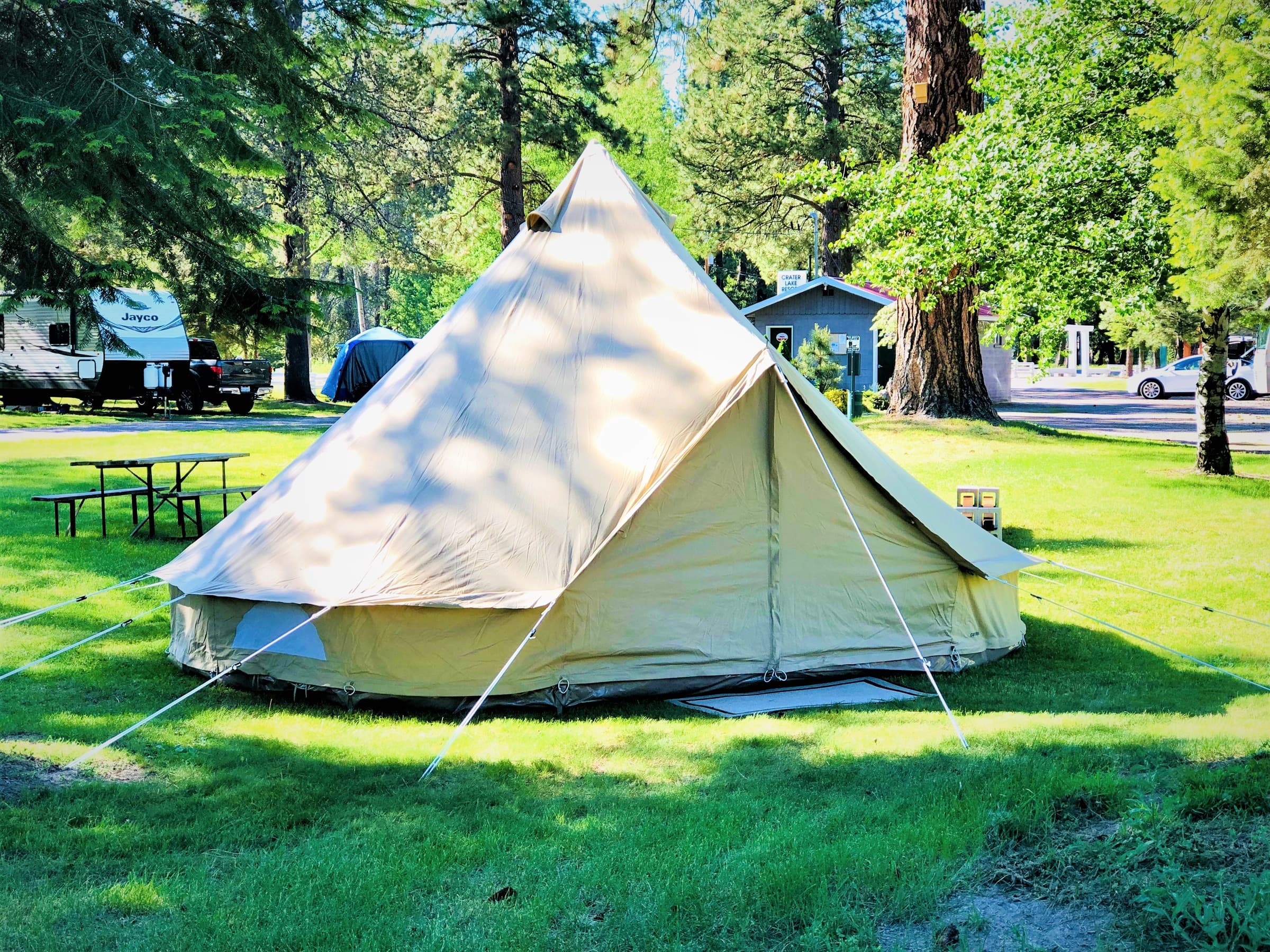 Bell tent on the lawn with a picnic table beside it