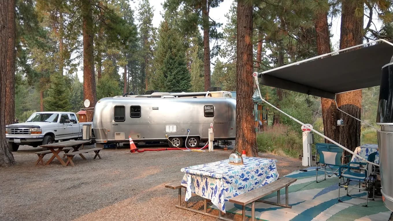 Airstream with awning extended, picnic table and camp chairs at the RV site