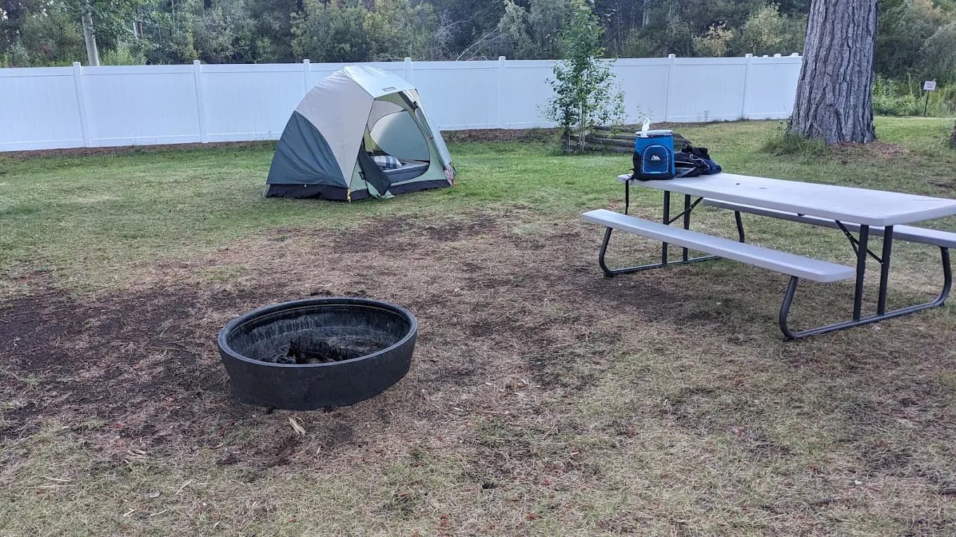 Dome tent on a grass tent site with picnic table and fire ring