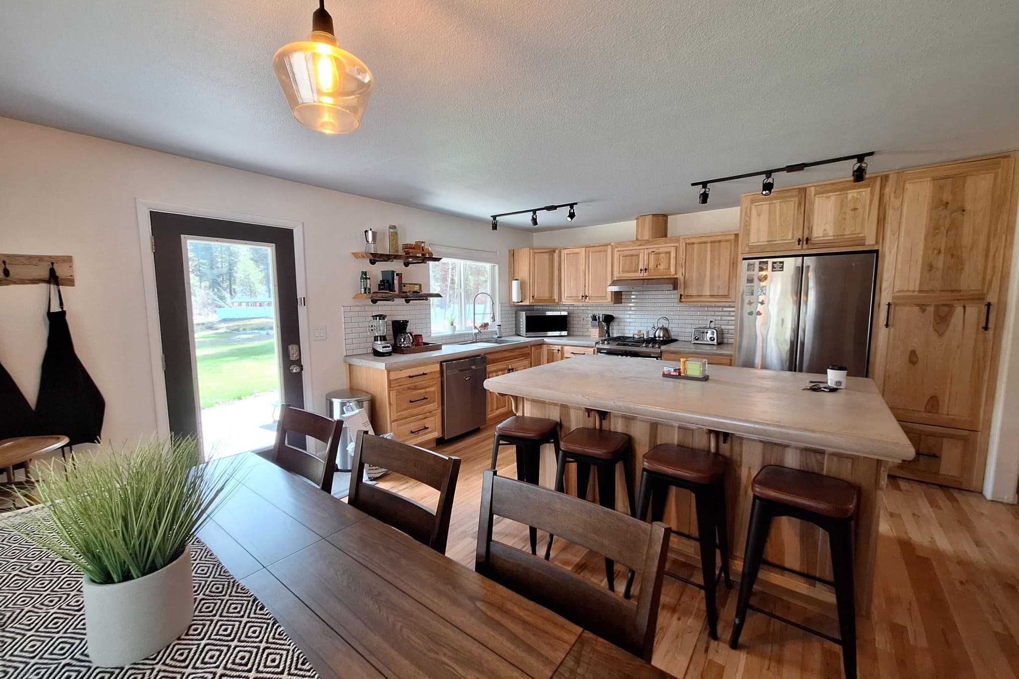 Full hickory kitchen with island, four barstools, and dining table