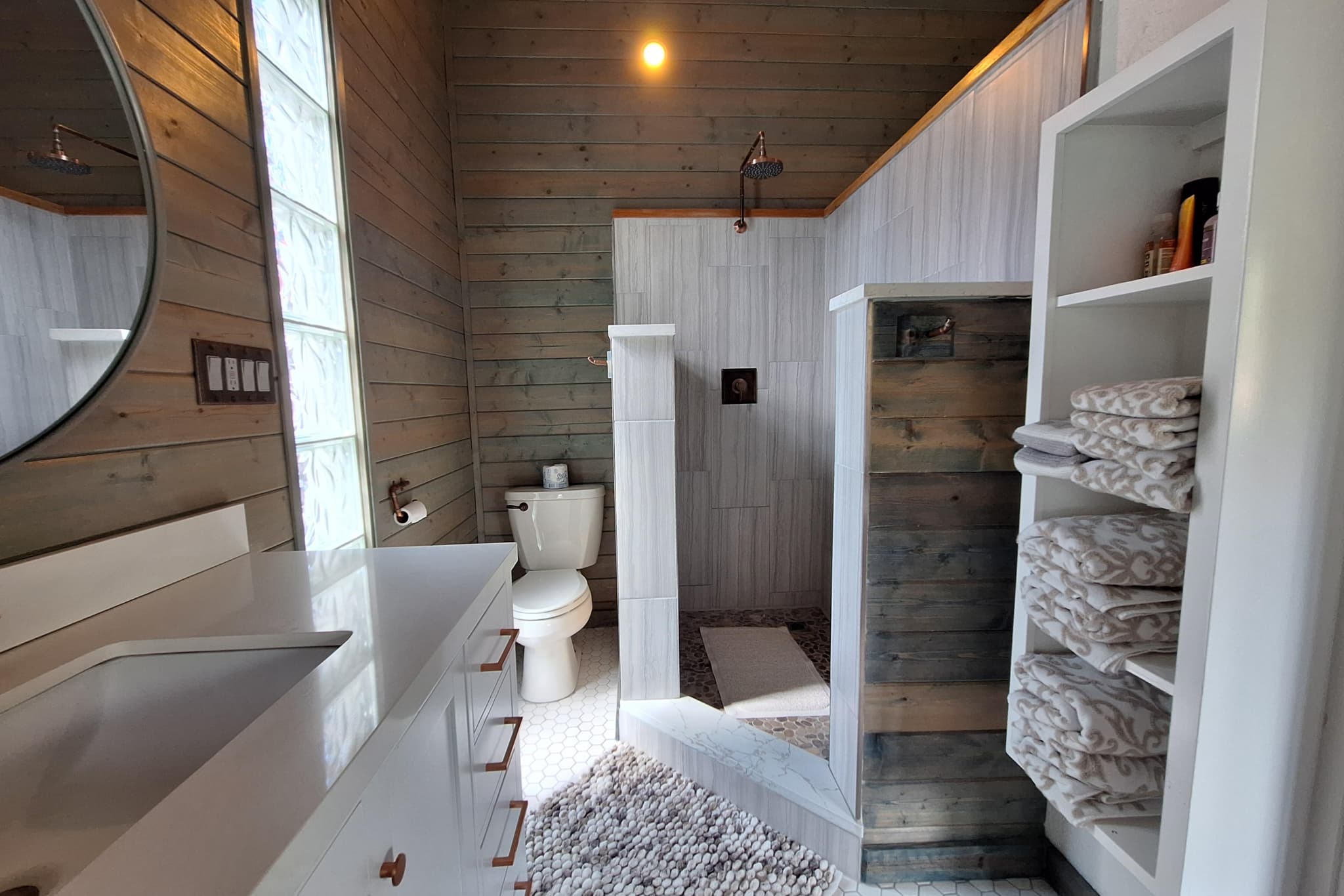 Master bathroom with wood-plank walls, glass shower, stone tile