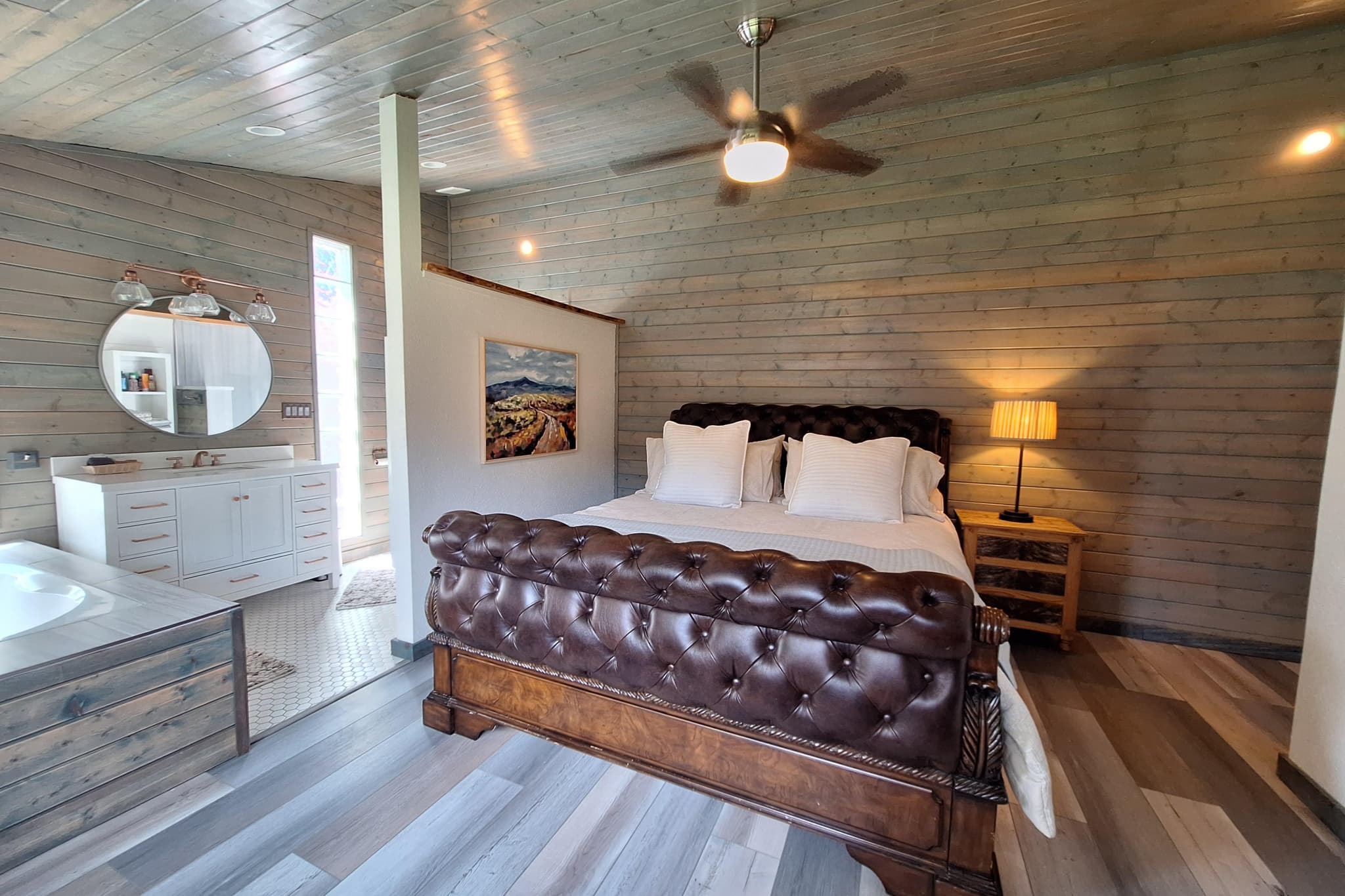 Master bedroom with king tufted leather bed, wood-plank walls, jacuzzi